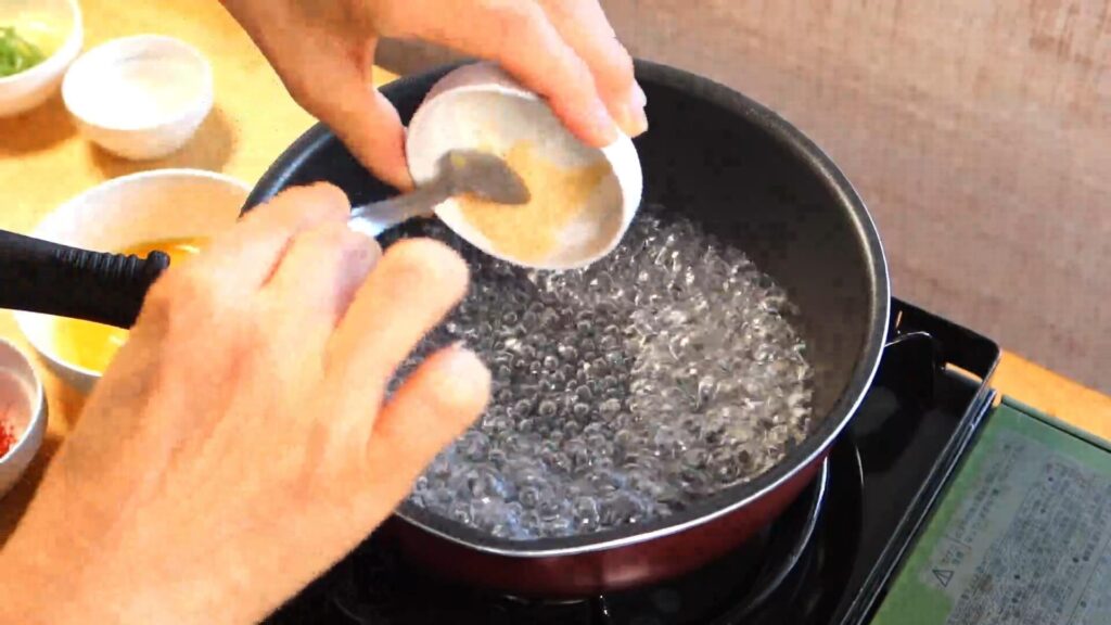 鍋に入れた水に鶏がらスープの素を入れている画像