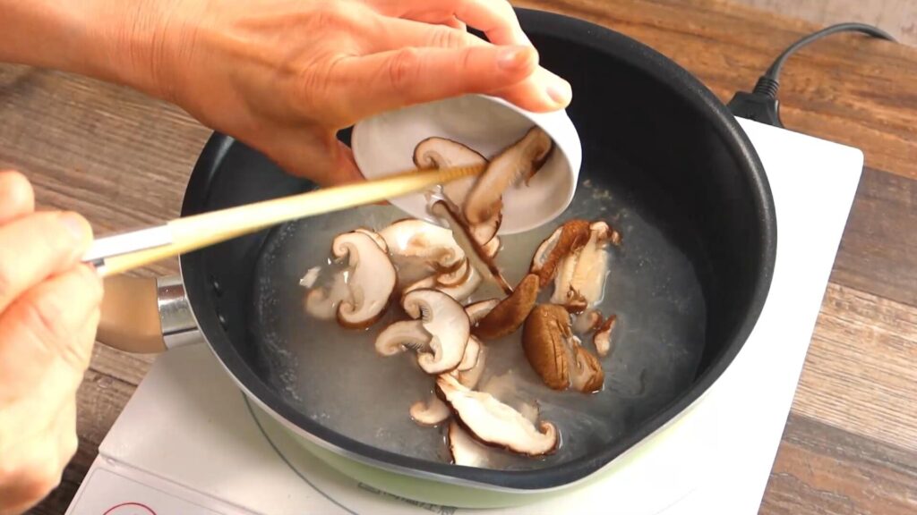 鍋に椎茸を入れている画像