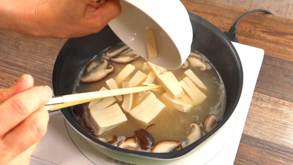 豆腐を鍋に入れている画像