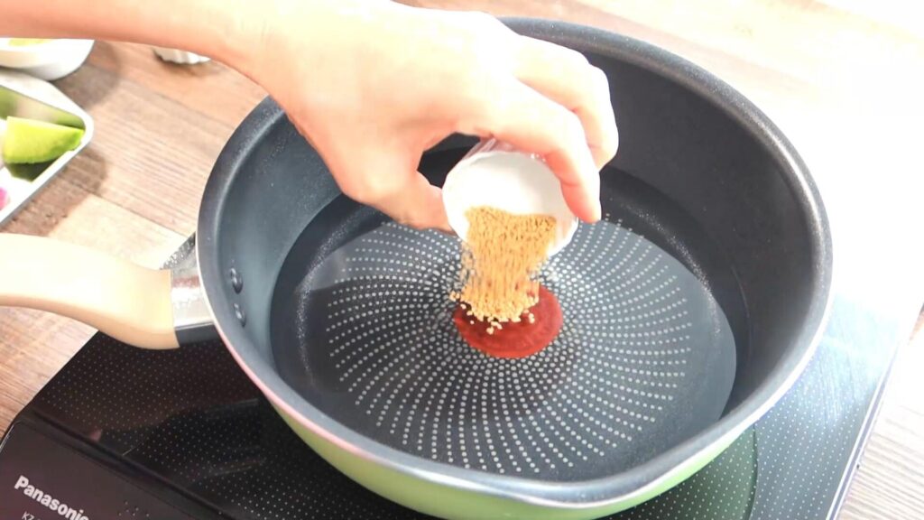 鍋にコンソメ顆粒を加えている画像