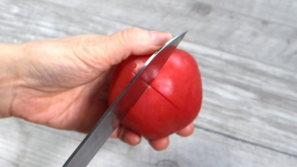 トマトに十字の切り込みを入れている画像。