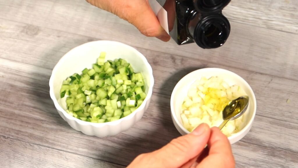 さいの目に切ったセロリときゅうりにオリーブオイルを加えている画像
