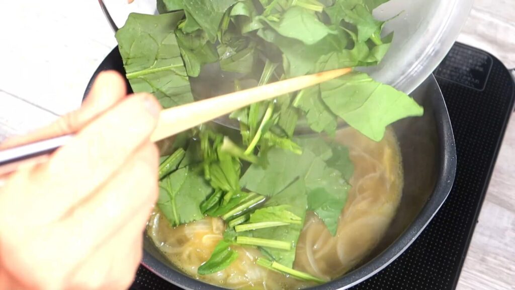 鍋にほうれん草を入れている画像