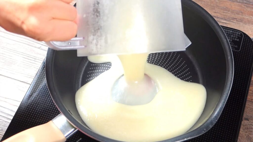 撹拌したスープを鍋に入れている画像